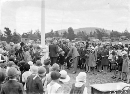 Mrs Bruce receiving a bouquet with a crowd of children at opening of Ainslie School.