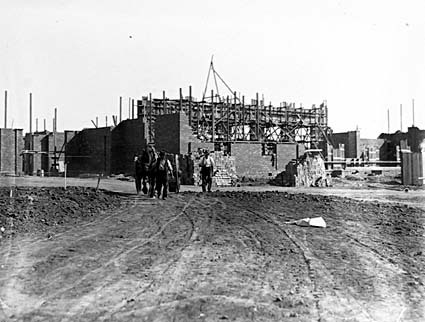 Building under construction with horse and cart in foreground