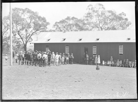 School building with children and crowd at the opening of Mount Russell School, Canberra.