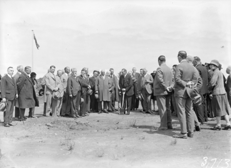 Part of crowd with Rt Hon S M Bruce on shovel.