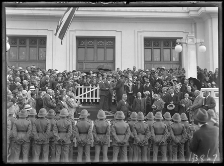Presentation of cheque and cigarette case to Bert Hinkler by Prime Minister S.M. Bruce in front of Parliament House with Royal Military College Cadets and spectators.
