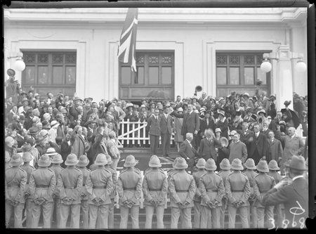 Bert Hinkler being welcomed by Prime Minister S.M. Bruce in front of Parliament House with Royal Military College Cadets and spectators.