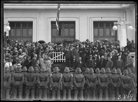 Bert Hinkler being welcomed by Prime Minister S.M. Bruce in front of Parliament House with Royal Military College Cadets and spectators.