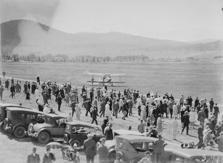 Arrival of Captain W.N. Lancaster and Mrs Keith Miller at the Review Ground opposite Hotel Kurrajong, aircraft taxing after landing.