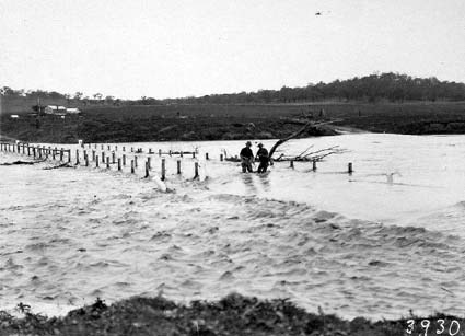 Floodwaters at Scotts Crossing.Workmen removing bridge rails and flood debris