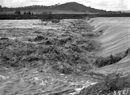 Flood waters overflowing the Kingston Power Station weir. Edlingtons dairy at foothills of Mt. Pleasant.
