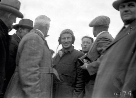 Kingsford Smith in flying helmet with crowd