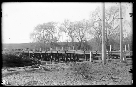 Scotts Crossing Bridge over Molonglo River after flood (was called Church Crossing because of parishioners travelling to St John's Church). Flood debris on bridge. Trees in river are Weeping Willows.