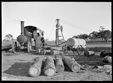 Steam traction engine operating a pile driver. Mobile water tank on right.