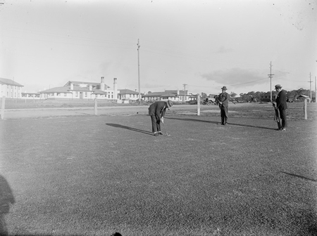 Three golfers on the putting green behind the Hotel Canberra.