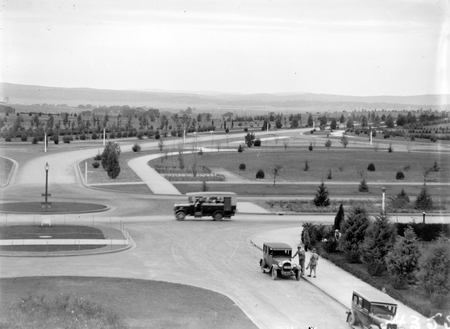 Bus passing West block on Queen Victoria Terrace, showing young trees.