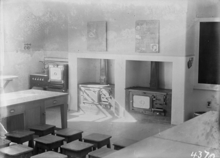 Kitchen at Technical Trades School with a recipe for a sponge cake, two wood stoves and an electric stove.