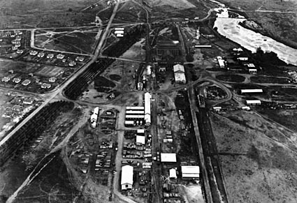Aerial view above Kingston looking west over Kingston Power Station.shows railway line for coal deliveries,concrete pipe works, saw mill, ice works and Mologlo River backed up by the weir