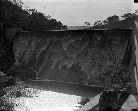 Cotter Dam wall with water flowing over the spillway into the stilling pond