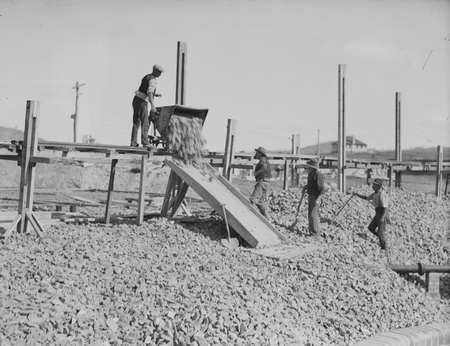 Workman pouring screenings from skip at trickling filters. Weston Creek sewerage treatment works.