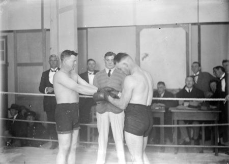 Two boxers meeting in the ring. Referee was Archie Hamilton, boxers were Kid Dempsey, other unknown. Probably in the Causeway Hall.