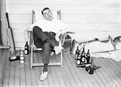 Cricketer  sleeping in a deckchair with refreshments and cricket gear, awaiting his innings.