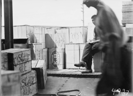 First consignment of liquor following the lifting of Probition in the ACT. Railway truck load of beer cases with a tally clerk.