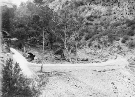 Cotter Dam below the wall; stilling pond is dry. Footbridge across Cotter River on the left.