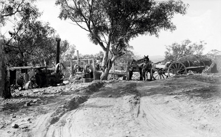 Mobile steam power plant driving a rock breaker with drays carrying rock for road construction