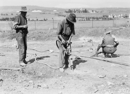 Workmen with jackhammer for road work construction.
