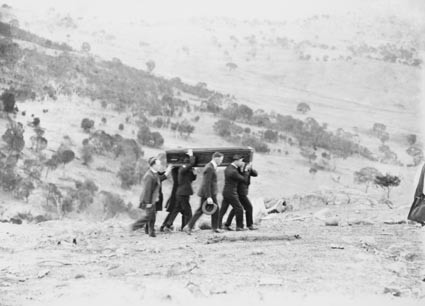 Funeral of Director of Commonwealth Solar Observatory, Dr. W G Duffield on Mt Stromlo. Pallbearers with the coffin proceding to the gravesite