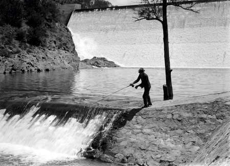 Cotter Dam Wall and stilling pond. Fisherman fly casting into the pond