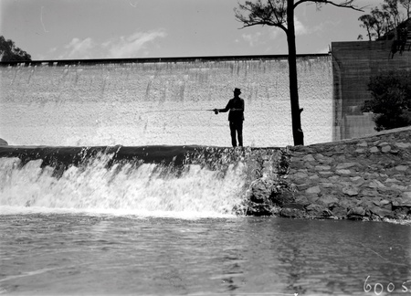 Cotter Dam Wall and stilling pond. Fisherman fly casting into the pond