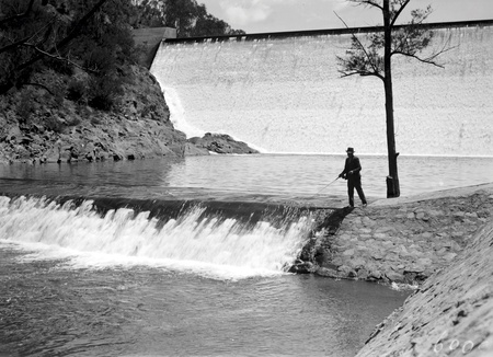 Cotter Dam Wall and stilling pond. Fisherman fly casting into the pond
