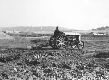 Fordson wheeled tractor hauling a scoop