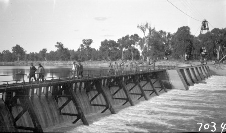 Murray River Commission. Unidentified group walking across a weir on the Murray River.