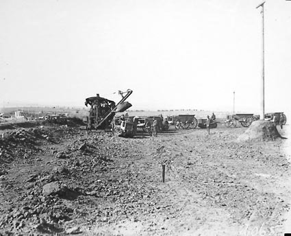 Steam traction engine towing a digger loading earth into crawler tractor drawn wagons