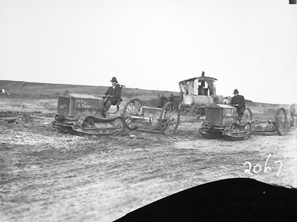 Two Cletrac crawler tractors towing scoops - Steam excavator in background