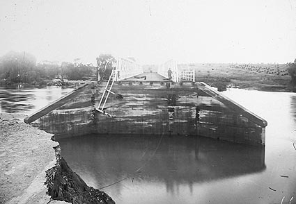 Commonwealth Bridge showing flood damage with the abutments washed away. Molonglo River in flood