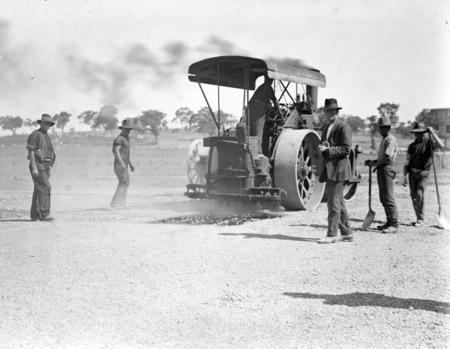 Steam roller road building with workmen.