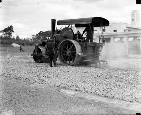 Steam roller with attached tar spray at work making roads near Parliament House